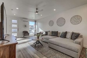 A modern living room with a sofa, coffee table, and a television. - The Lofts #36 | Townhome Pool Resort (Saint George)