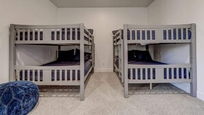 A room with two bunk beds, a small blue bean bag, and a carpeted floor. - The Lofts #36 | Townhome Pool Resort (Saint George)