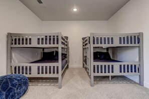 A room with two bunk beds, a small blue bean bag, and a carpeted floor. - The Lofts #36 | Townhome Pool Resort (Saint George)