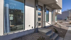 A modern building with large windows, a visible door, and a staircase leading to the entrance. - The Lofts #36 | Townhome Pool Resort (Saint George)