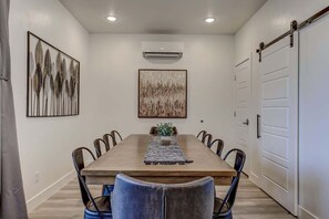 Une salle à manger avec une table rectangulaire, six chaises et une plante placée au centre.