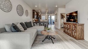 A modern living room with a sofa, a coffee table, and a TV. - The Lofts #36 | Townhome Pool Resort (Saint George)