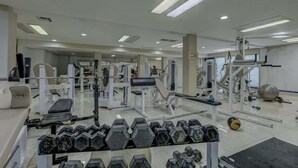 Un gimnasio con equipos de ejercicio variados, incluyendo mancuernas, cintas de correr y máquinas de pesas.