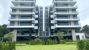 A modern multi-story building with a symmetrical facade, large windows, and balconies. - Gorgeous Sunset View ❤︎ Mae Phim Beachfront Condo (Kram)