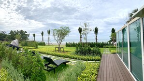 A garden with a wooden deck, a lawn, and a view of the beach. - Gorgeous Sunset View ❤︎ Mae Phim Beachfront Condo (Kram)