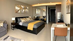 A modern hotel room with a large bed, bedside tables, a desk, and a chair. There are multiple artworks on the walls and a mirror reflecting the room. - Gorgeous Sunset View ❤︎ Mae Phim Beachfront Condo (Kram)