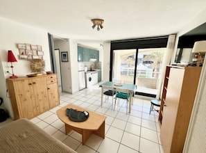 Ein kompakter Wohnbereich mit Küchenzeile, Essbereich und Blick durch ein großes Fenster.
