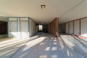 Enter a grand hall with a high ceiling and central light fixture, surrounded by neutral-toned walls and a wooden gate leading to an outdoor area.