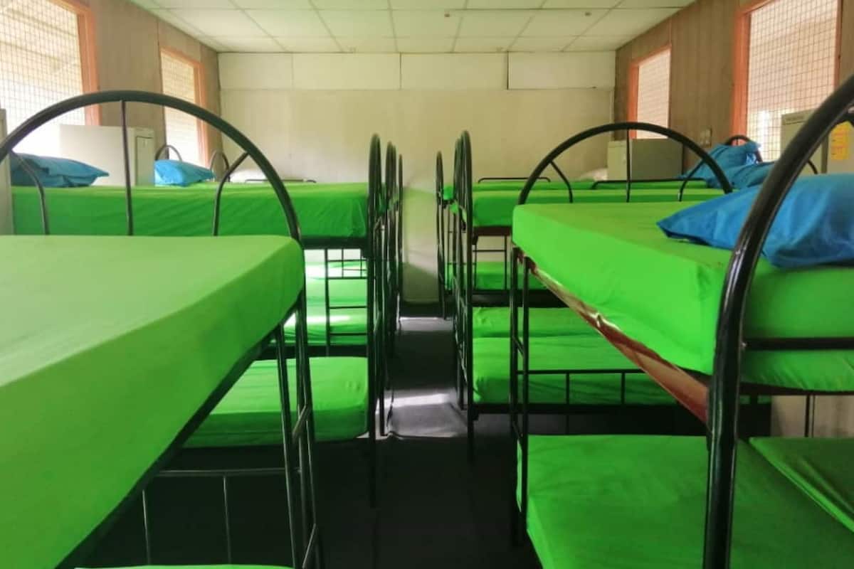 Ein Schlafsaalzimmer mit Etagenbetten, jeweils mit einer grünen Matratze und blauen Kissen.