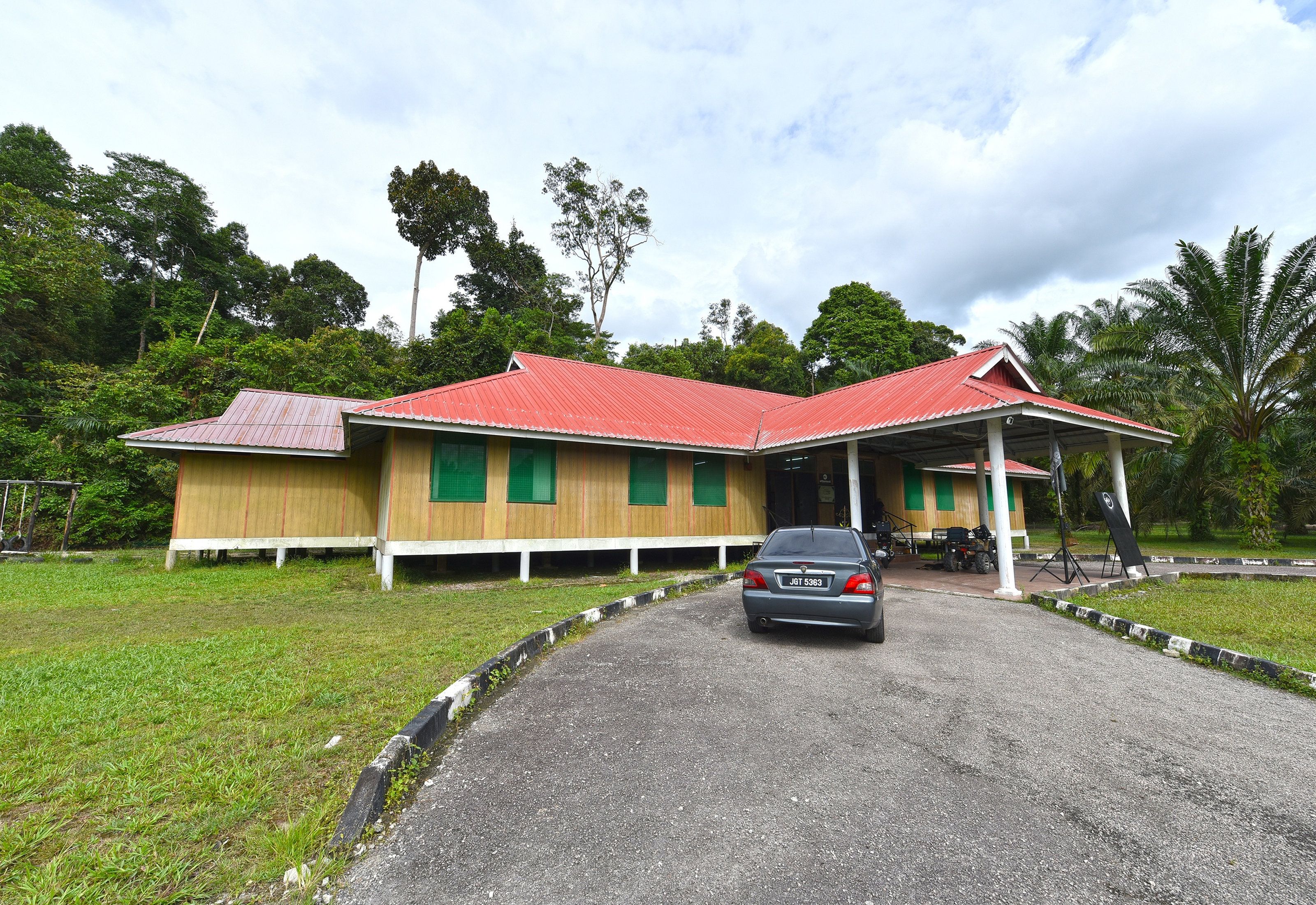 A building with a red roof, a covered porch, and a gravel driveway.