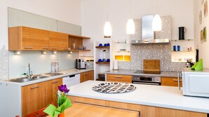 A modern kitchen with wooden cabinets, a white countertop, and pendant lighting. - Ferienwohnung ALEX (Burgau)