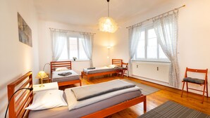 A room with two wooden beds, a wooden chair, a table, and a lamp. - Ferienwohnung ALEX (Burgau)