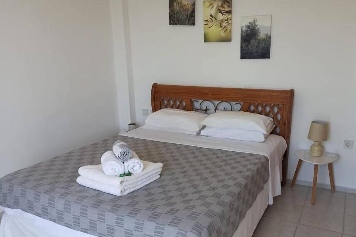 A neatly made bed with a patterned bedspread, a wooden headboard, and a small bedside table with a lamp.