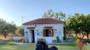 Un petit bâtiment avec un toit recouvert de tuiles rouges, une façade blanche et une porte dotée d’une fenêtre.