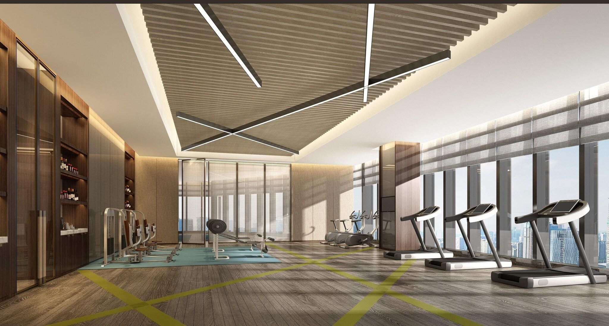 Un gimnasio moderno con equipo de ejercicio, ventanas amplias y un techo alto.