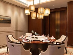 A conference room with a round table, chairs, and pendant lighting.