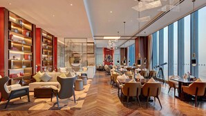 A modern hotel lobby with a large seating area, a bar, and a view of the city. - Pullman Huizhou Kaisa (Huizhou)