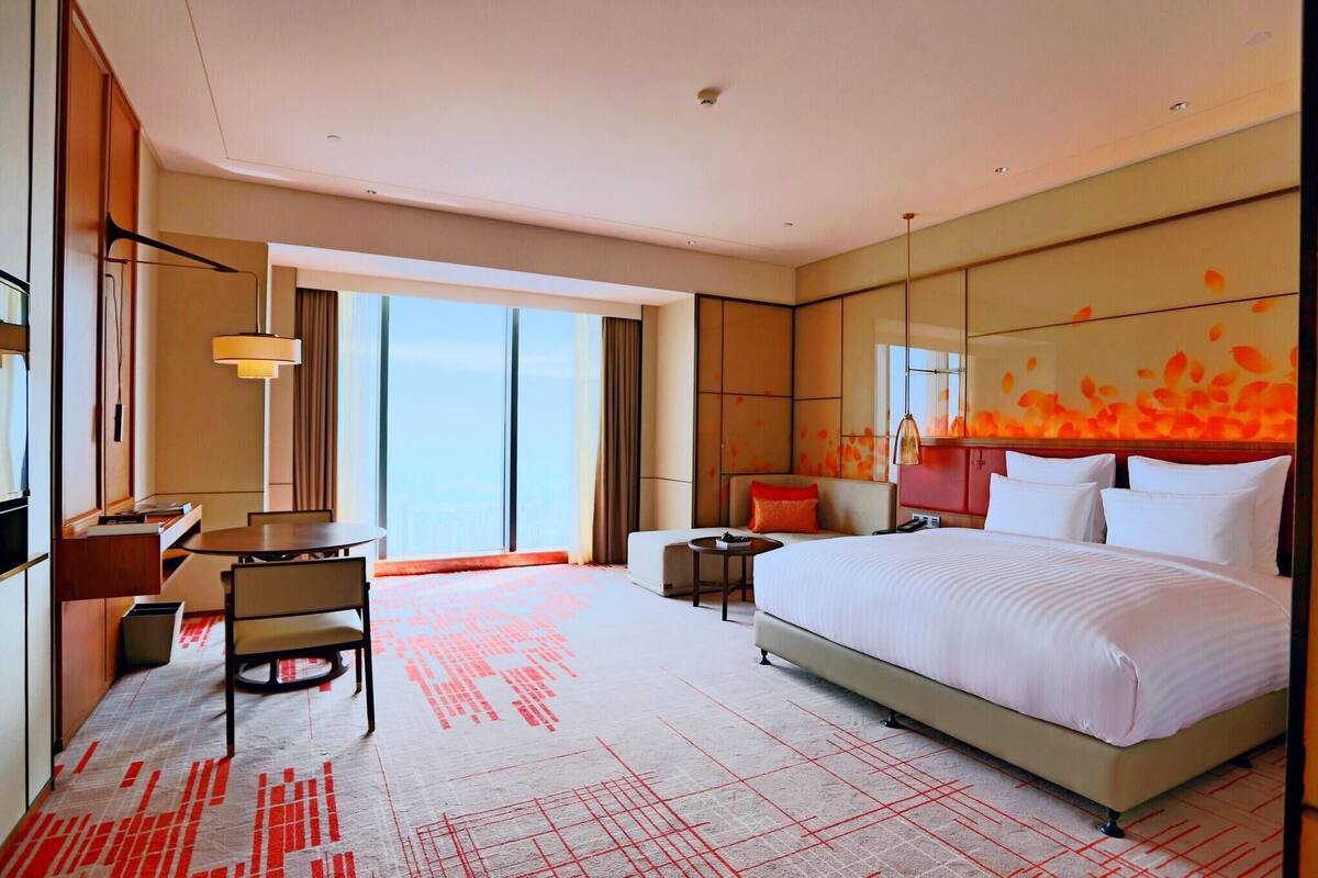 Quarto de hotel com uma cama grande, uma mesa de escritório, uma cadeira, uma mesinha e um sofá.