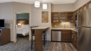 A compact hotel room with a kitchenette, a dining area, and a bed. - Staybridge Suites Overland Park - Kansas City S (Overland Park)