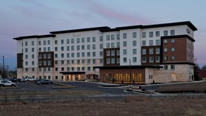 A multi-story hotel with a modern design, featuring a central courtyard and a parking lot. - Staybridge Suites Overland Park - Kansas City S (Overland Park)