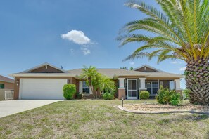 A two-story house with a garage, a well-maintained lawn, and a palm tree.