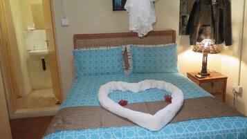 Un dormitorio con cama, alfombra con forma de corazón, lámpara y perchero.
