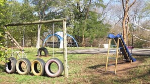 Une aire de jeux avec des balançoires, des pneus suspendus et un toboggan.