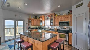 A kitchen with wooden cabinets, a large island with stools, a view to the outside, and a sign that reads "LA TRATORIA". - Bayfront Fishing Pier: Galveston Island Home! (Galveston)