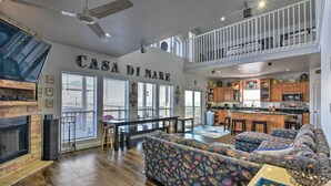 A spacious living area with a fireplace, a large sofa set, a dining table, and a kitchen in the background. - Bayfront Fishing Pier: Galveston Island Home! (Galveston)
