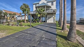 A beachfront property with a paved walkway, palm trees, and a two-story house with a balcony. - Bayfront Fishing Pier: Galveston Island Home! (Galveston)