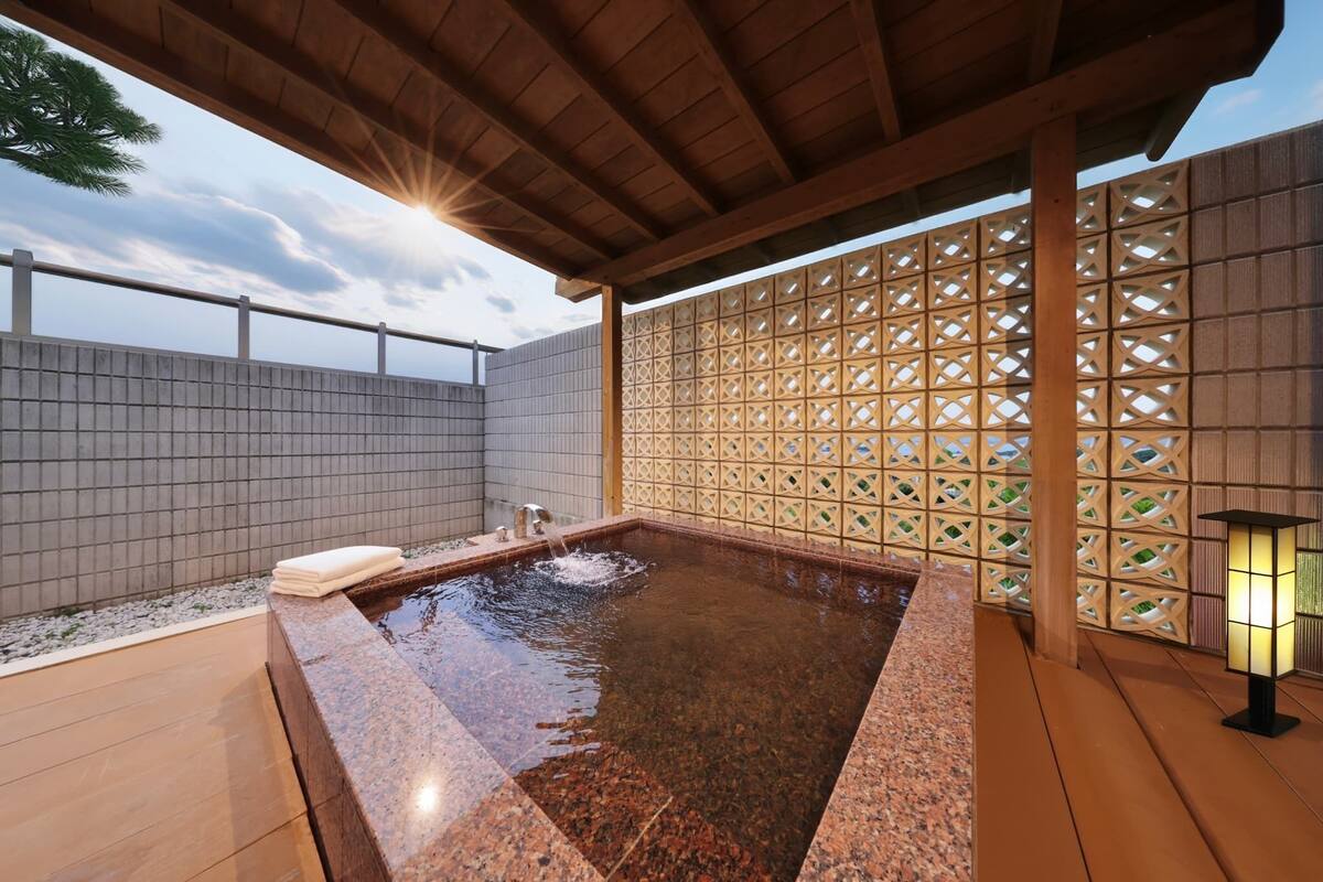 A spa area with a hot tub, wooden deck, tiled walls, and a decorative lattice fence.