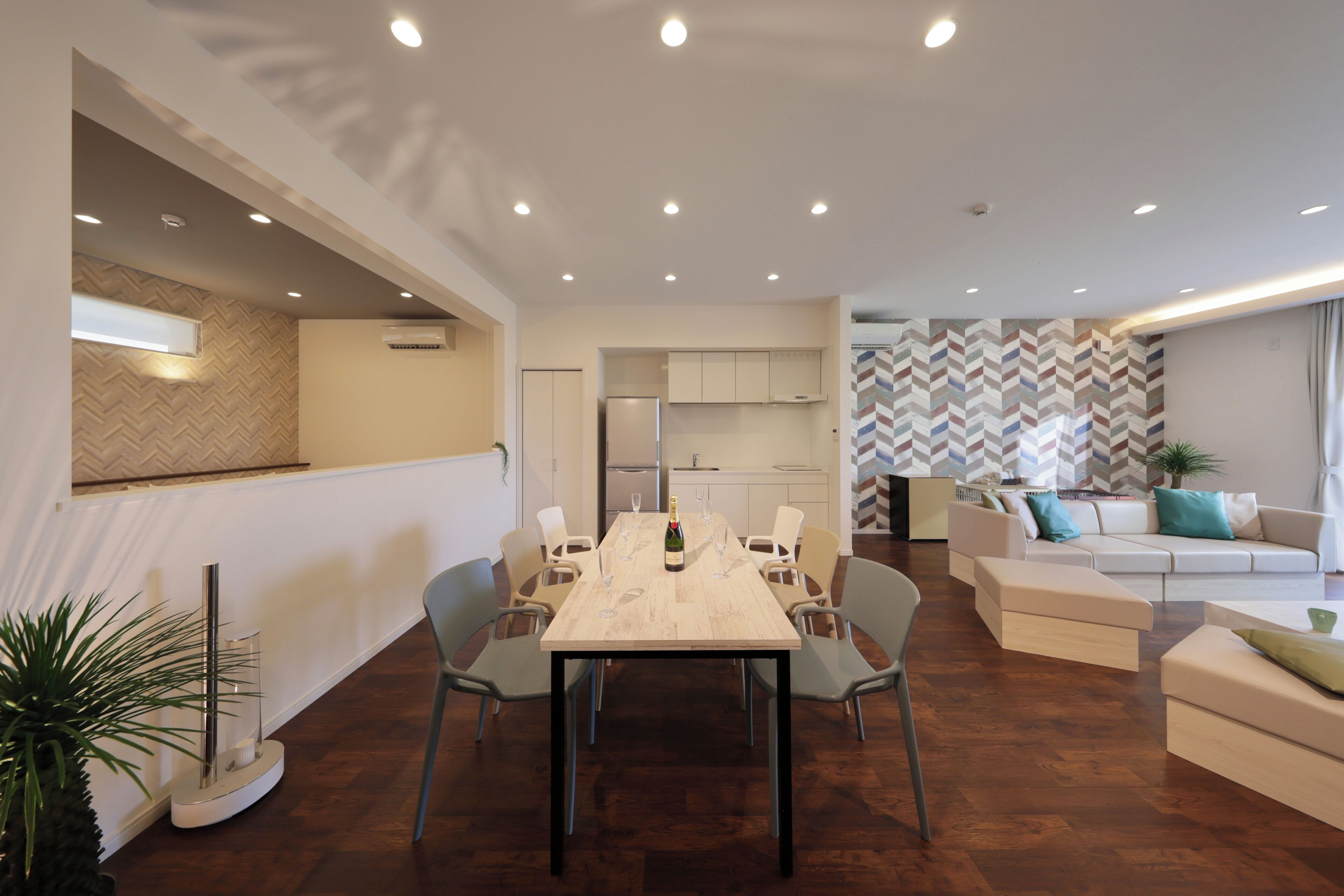 A modern living room with a dining area, a sofa set, and a kitchen in the background.