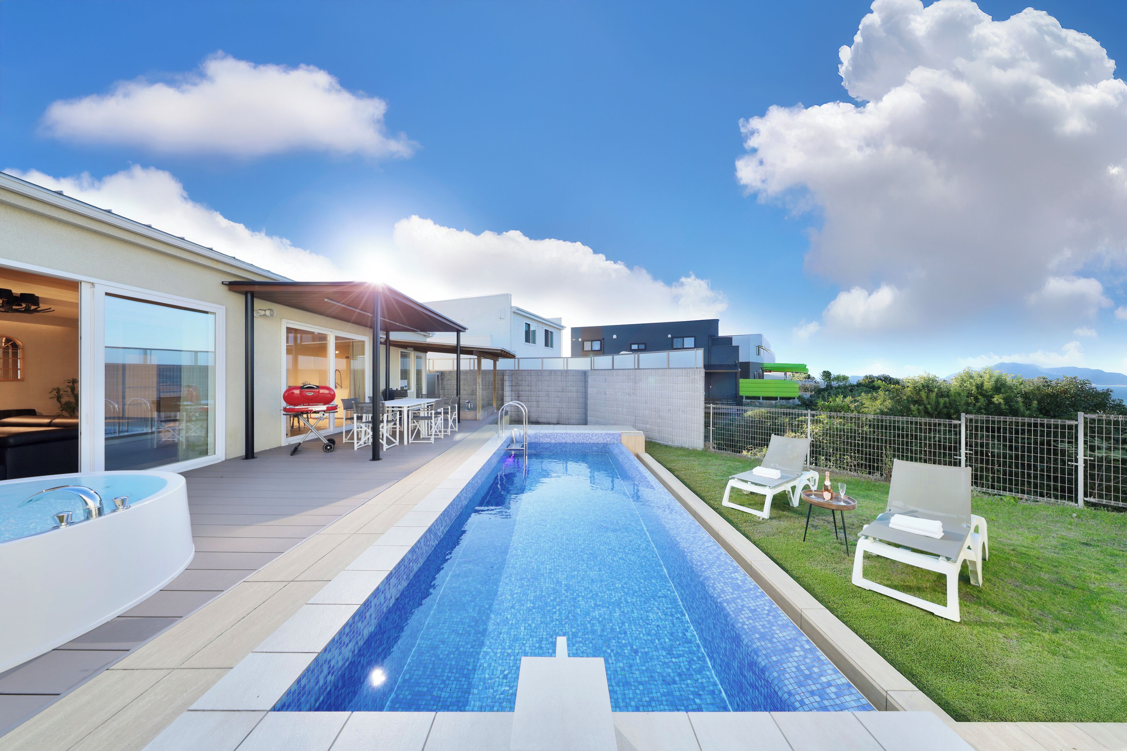 A modern outdoor pool area with a clear blue pool, a covered seating area, and a view of the surrounding landscape.
