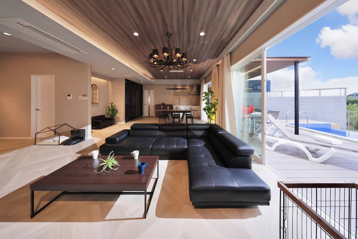 A modern living room with a large sectional sofa, a wooden coffee table, and a dining area in the background.