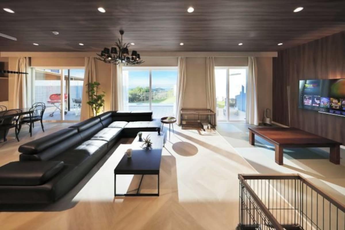 A modern living room with a black sectional sofa, a small coffee table, and a TV mounted on the wall.
