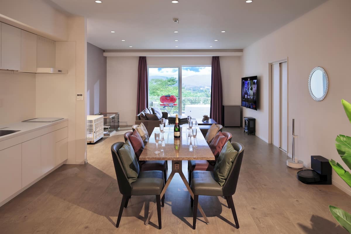 A modern dining area with a long table, comfortable chairs, and a view of the outdoors.