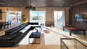 Ein modernes Wohnzimmer mit einem großen, schwarzen Ecksofa, einem Couchtisch und einem an der Wand montierten Fernseher.
