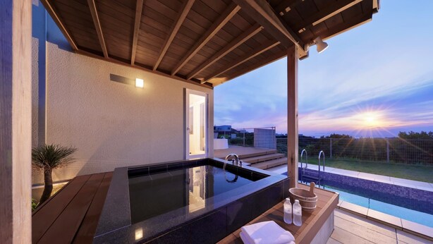 Wellnessbereich mit Whirlpool, Holzboden und Blick auf den Sonnenuntergang.