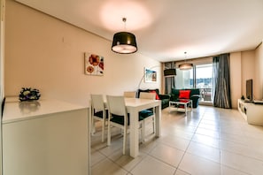 A modern living room with a dining area, a sofa, a TV, and a balcony with curtains. - Beautiful apartment with sea views in Altea Hills / Ref 1092 Elena Hills (Altea)