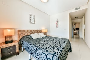 A bedroom with a patterned bedspread, a woven headboard, bedside lamps, and a wall decoration. - Beautiful apartment with sea views in Altea Hills / Ref 1092 Elena Hills (Altea)