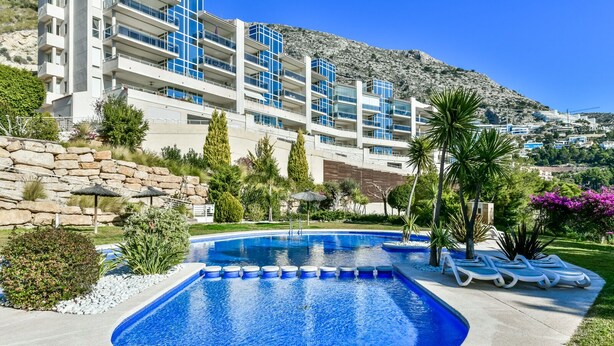 Ein Pool mit kreisförmigem Design, umgeben von Liegestühlen und einer Steinmauer.