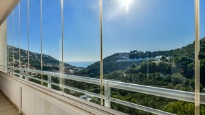 Ein Balkon mit freiem Blick auf eine Hügellandschaft mit Gebäuden und Grünflächen.