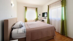 Une chambre à coucher avec un lit, une table de chevet, une télévision et des rideaux verts.