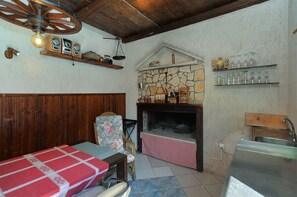 Eine rustikale Küche mit Kamin aus Stein, Holzbalken und kariertem Tischlein.