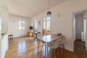 A spacious kitchen with a large wooden table, white chairs, and a hanging light fixture.