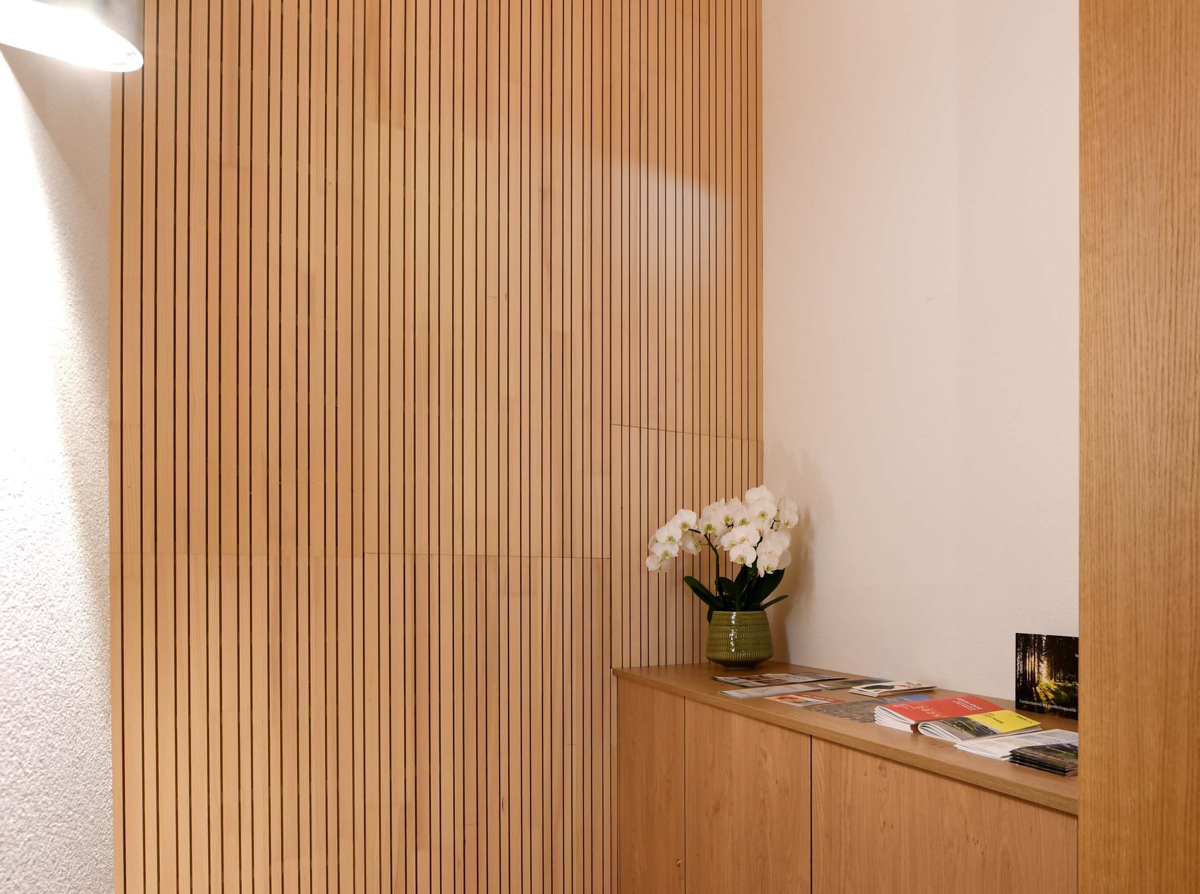A reception desk with a vase of white flowers, a green pot, and some magazines.