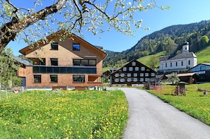 Un bâtiment moderne doté d’une grande façade en verre et d’une structure en bois traditionnelle, situé dans un cadre rural.