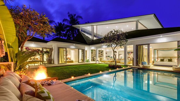 A modern house with a swimming pool, outdoor seating, and a well-lit interior. - Villa Momentai (Canggu)
