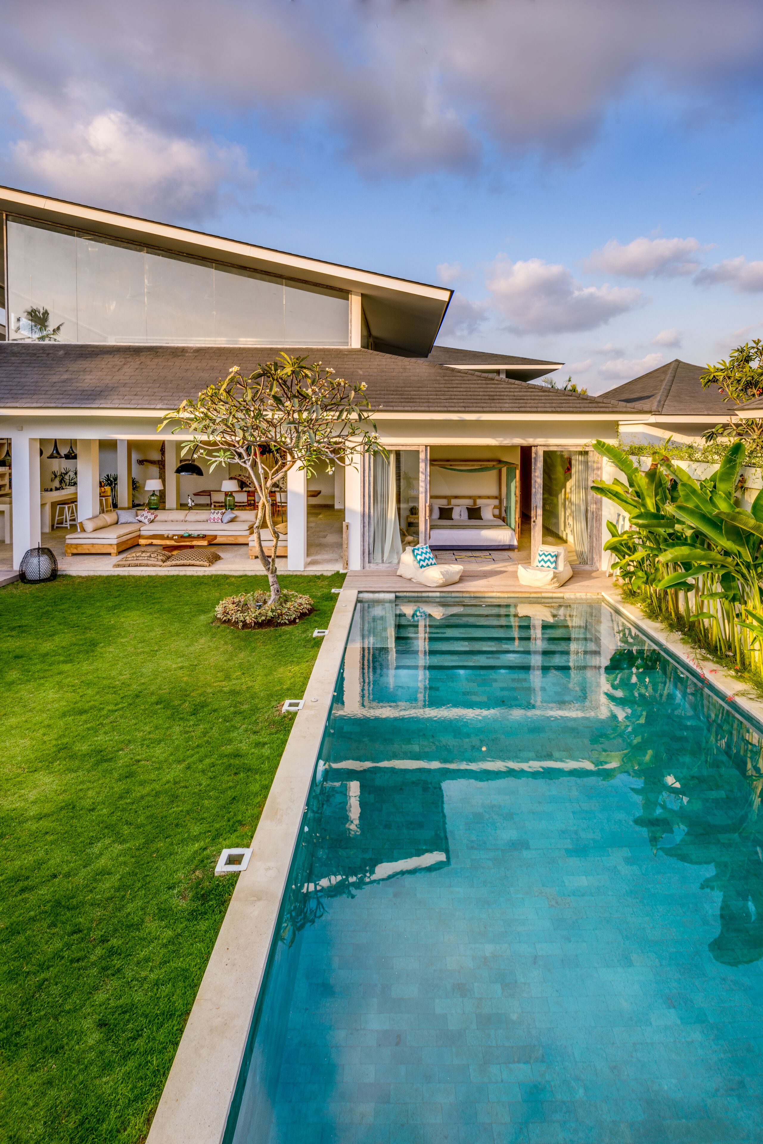 Uma casa moderna com piscina, gramado bem cuidado e área de estar com assentos.