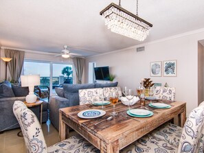 A dining area with a wooden table set for four, surrounded by patterned chairs.